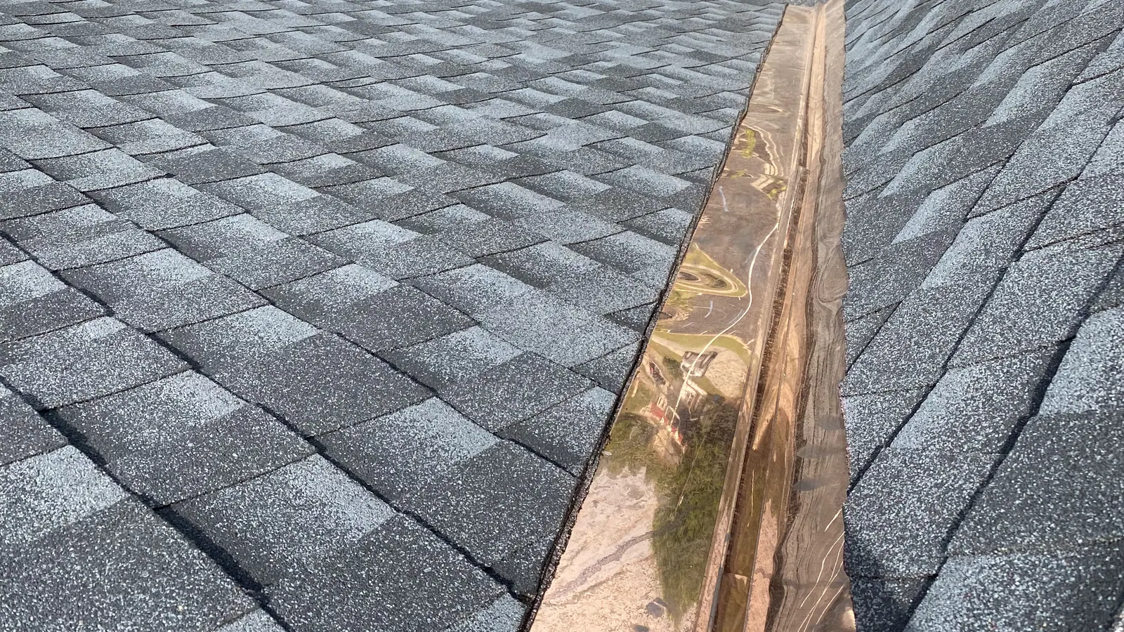 Newly installed seamless gutter running along the eave of a freshly shingled roof in the South Carolina Midlands