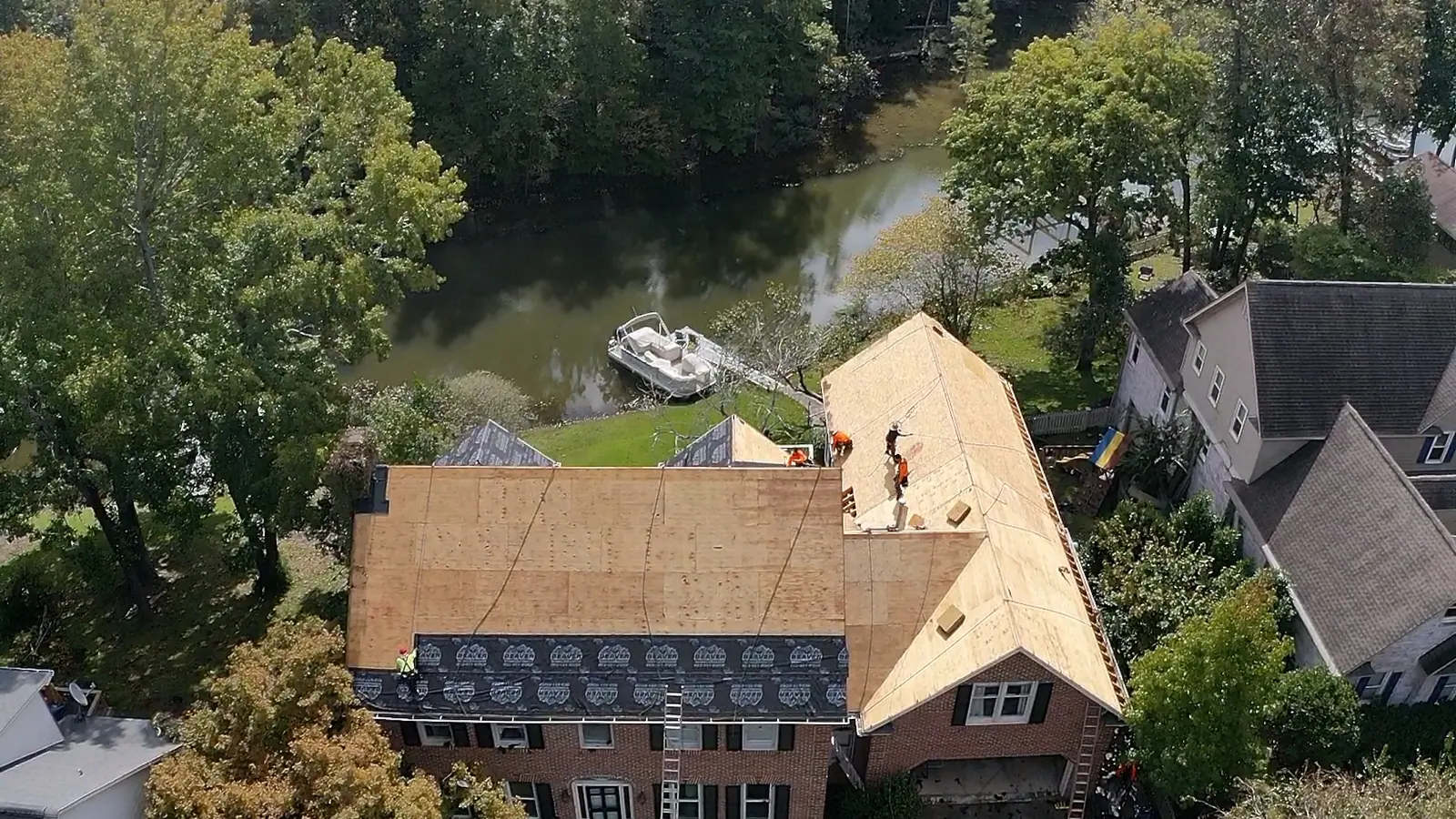 Aerial view of a roof replacement in progress with new decking exposed and the finished section already shingled