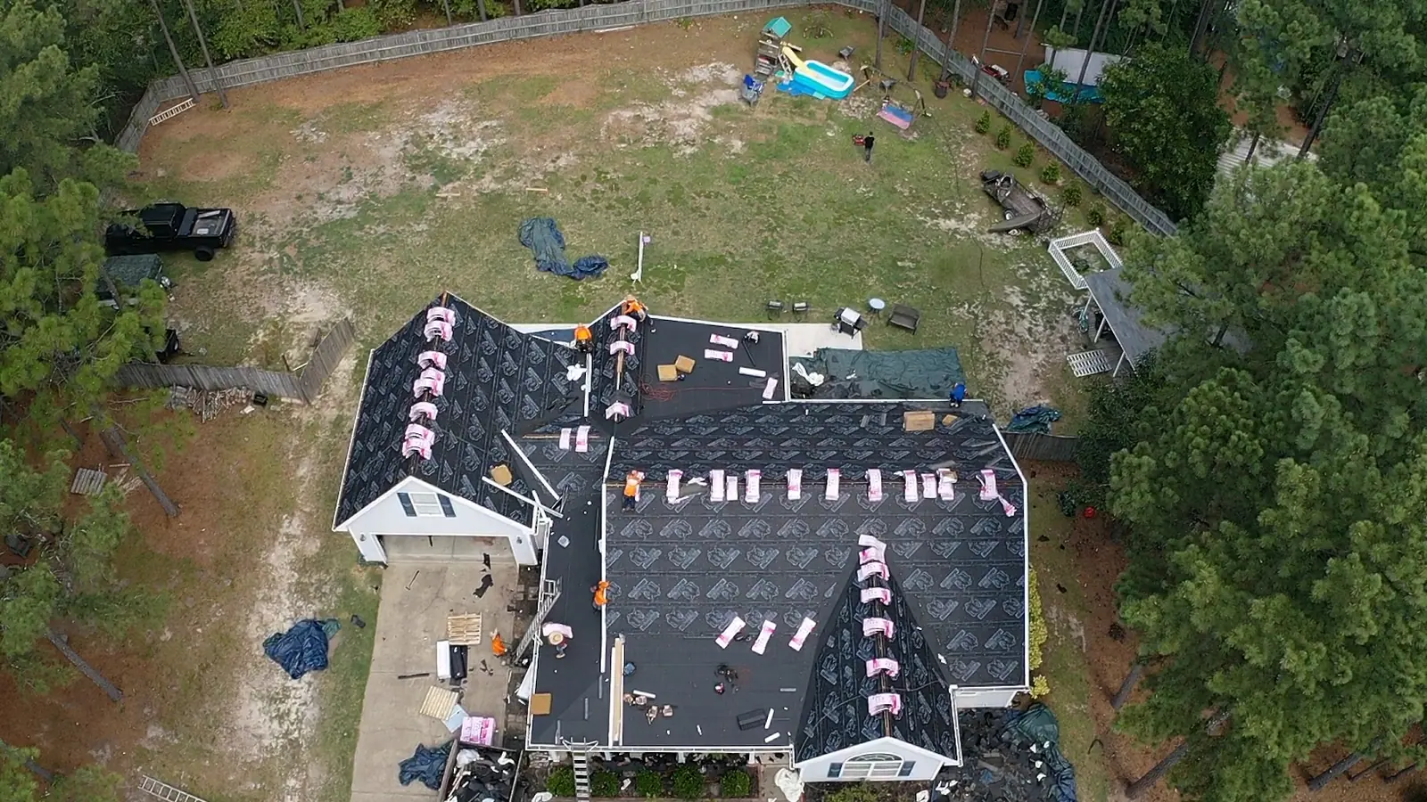 Aerial view of a roof replacement underway with the old shingles torn off and new bundles staged across the deck